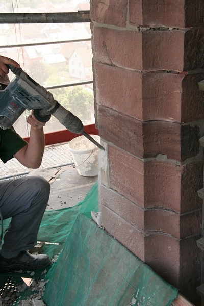 Handwerker mei&szlig;eln dann die alten Sockel aus dem Mauerwerk...