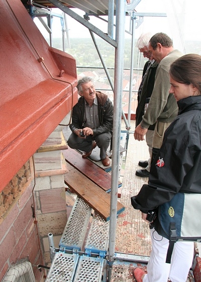 Da die Arbeiten am Turmhelm abgeschlossen sind, beginnt das Team direkt unterhalb des Turmhelms und arbeitet sich Etage für Etage nach unten durch.
Dabei wird der Turm auf jeder Ebene komplett umrundet.
