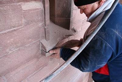 Die Turmfassade selbst weist ähnliche Schäden auf, wie das Mauerwerk am Turm.
Auch hier müssen brüchige Beton-Gesimse und Fensterbänke durch neue Sandsteinteile ersetzt werden.
Dieses Fensterbank konnte einfach vom Mauerwerk gelöst und von Hand herausgenommen werden.